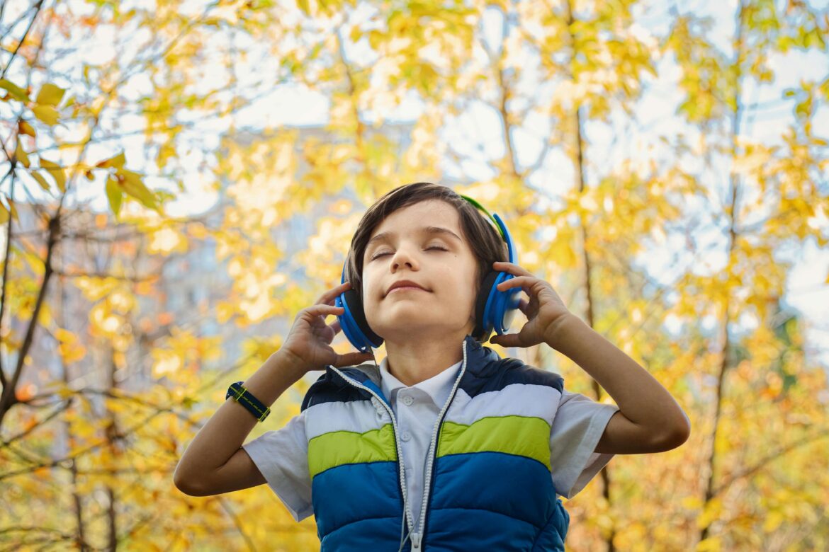 Chłopiec słucha muzyki, ucząc się angielskiego na dworze