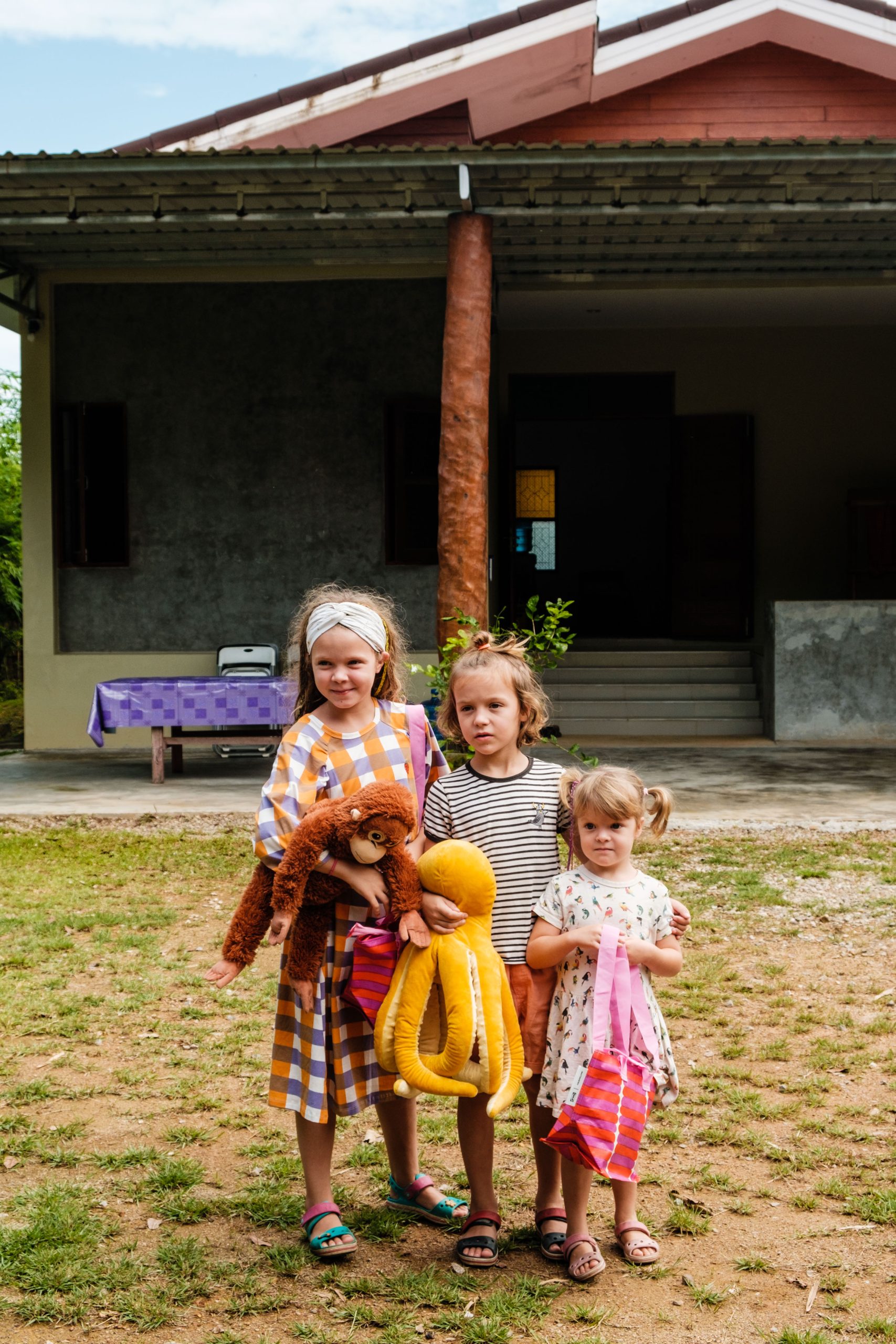 Troje dzieci stoi przed budynkiem na wyspie Lanta w Tajlandii.