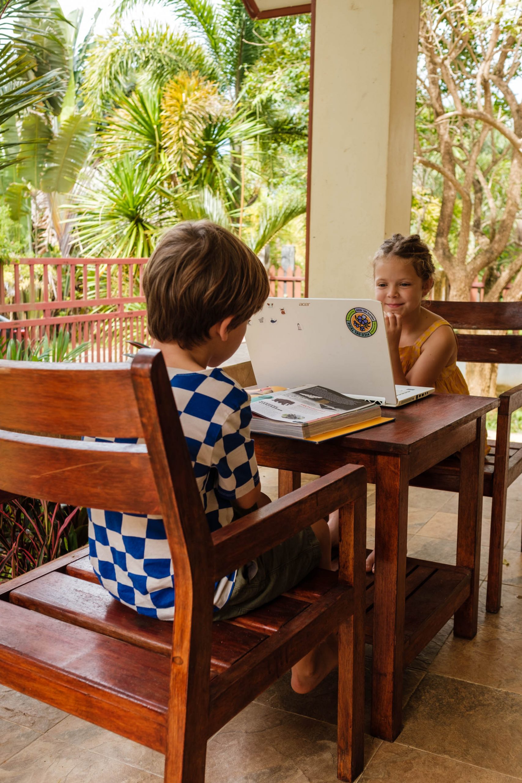Dwoje dzieci uczy się na zewnątrz przy stole.