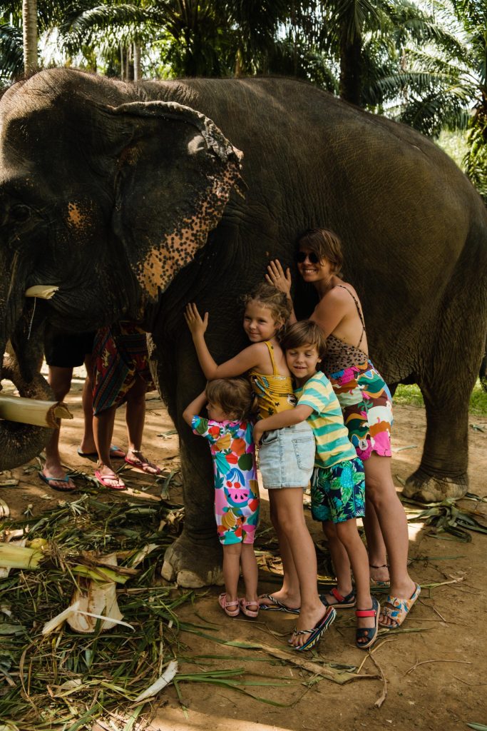 Matka z trójką dzieci przytulają słonia.