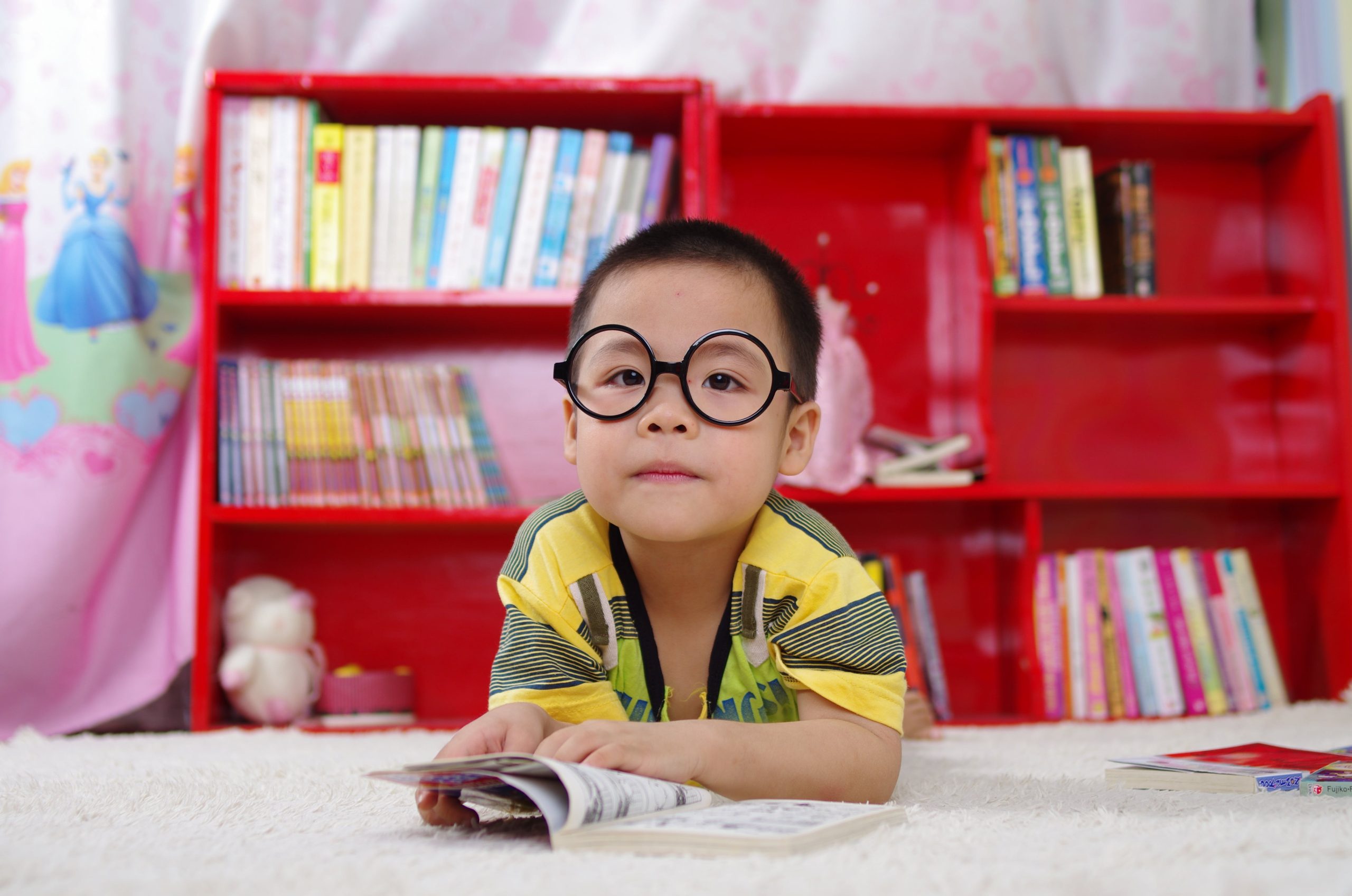 Chłopiec w okularach uczy się na tle książek.