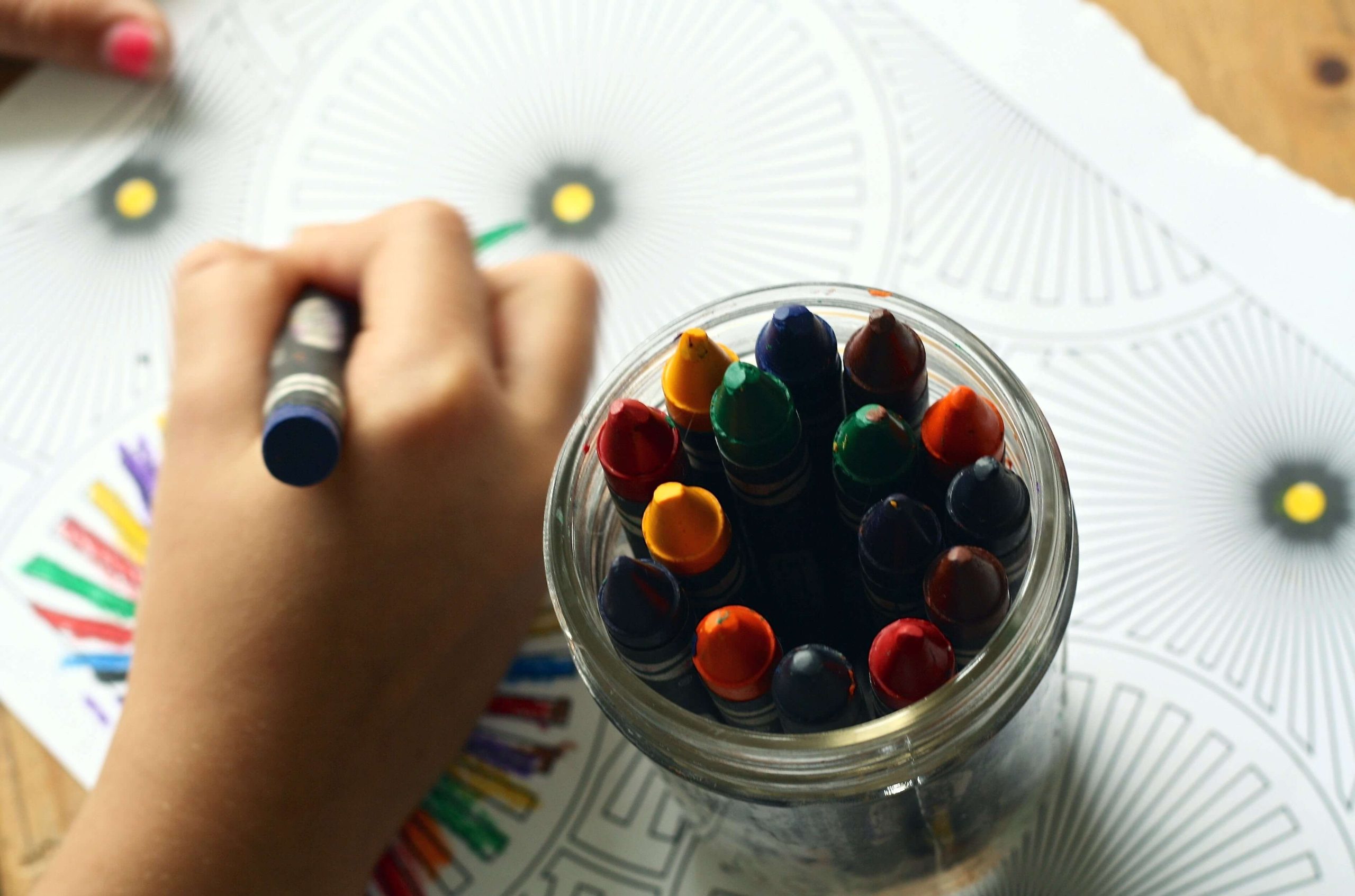 Dłoń dziecka kolorującego obrazek, aby nauczyć się angielskich słówek związanych z kolorami.