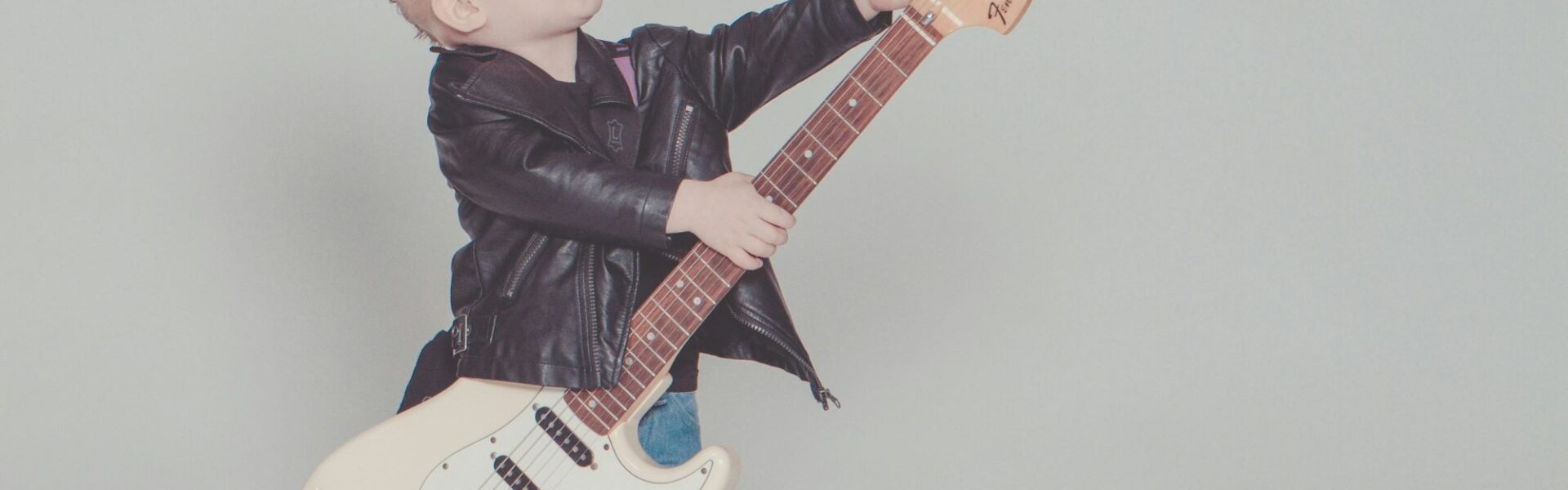 Gitara po angielsku, rock po angielsku - dziecko grające na gitarze elektrycznej. Jak uczyć się angielskich słówek związanych z muzyką?